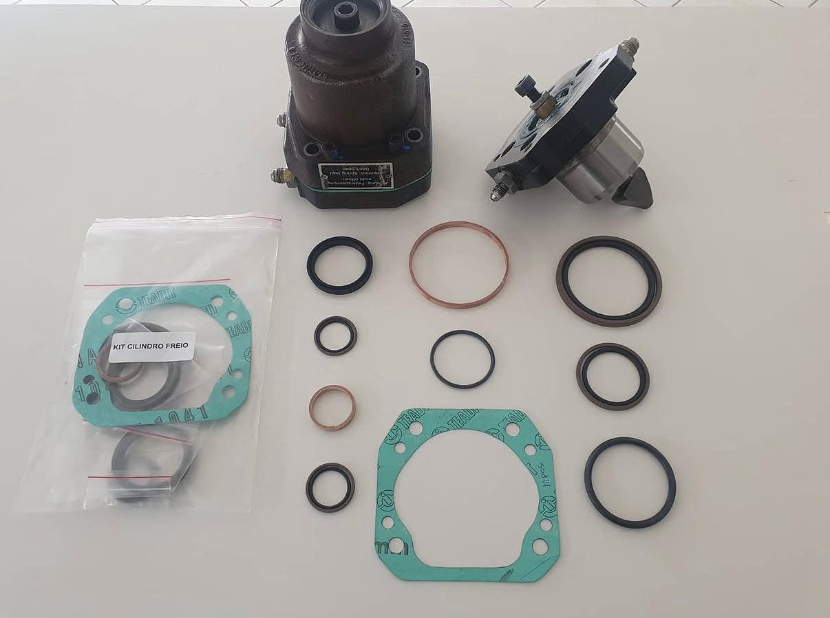 A detailed photographic close-up of forest machine spare parts laid out on a dark, non-reflective workshop surface: precision-machined gears, sprockets, high-pressure hydraulic hoses with fittings, valve blocks, filters, and reinforced bolts specific to forwarders and harvesters. Each part is clean and subtly oiled, with visible serial markings implied by tiny engraved areas, but no readable text. Overhead workshop lighting provides even, neutral illumination, creating crisp highlights and soft-edged shadows that accentuate shapes and textures. Captured from a top-down, flat-lay perspective with sharp focus across the frame, the overall mood is technical, meticulous, and trustworthy, underscoring the quality and reliability of specialized forest machinery components.